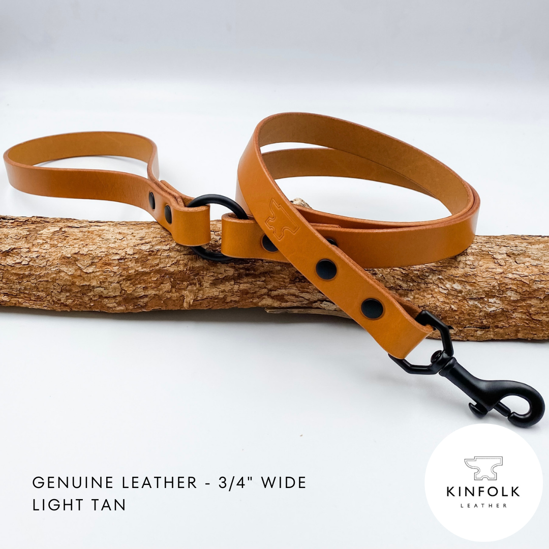 Light tan leather dog leash with black hardware on a wooden log against a white background, featuring the Kinfolk Leather logo.