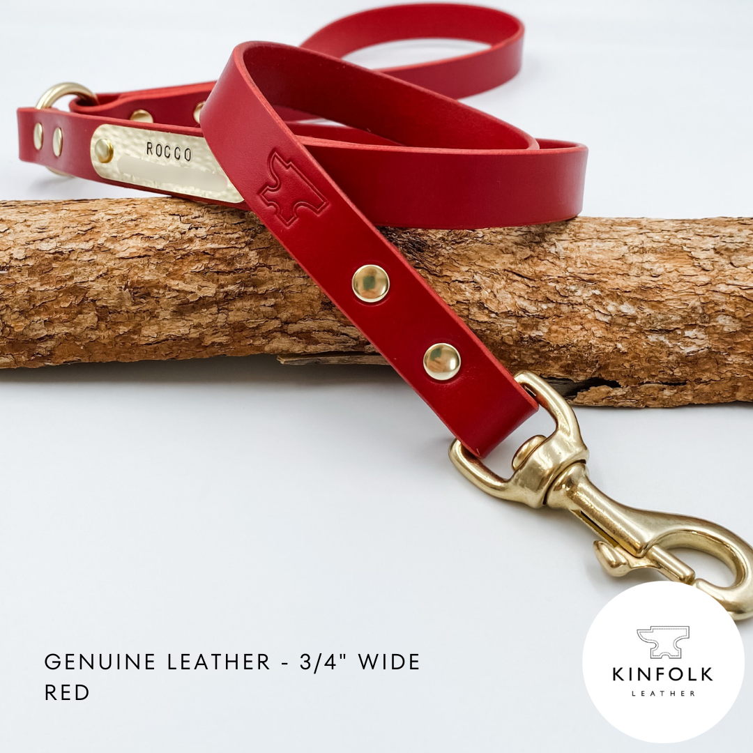 Red leather dog leash with gold hardware on a wooden branch, featuring the Kinfolk Leather logo.