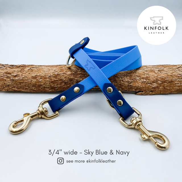 Blue and navy biotthane handsfree dog lead with gold hardware on a white background, featuring the Kinfolk Leather logo.